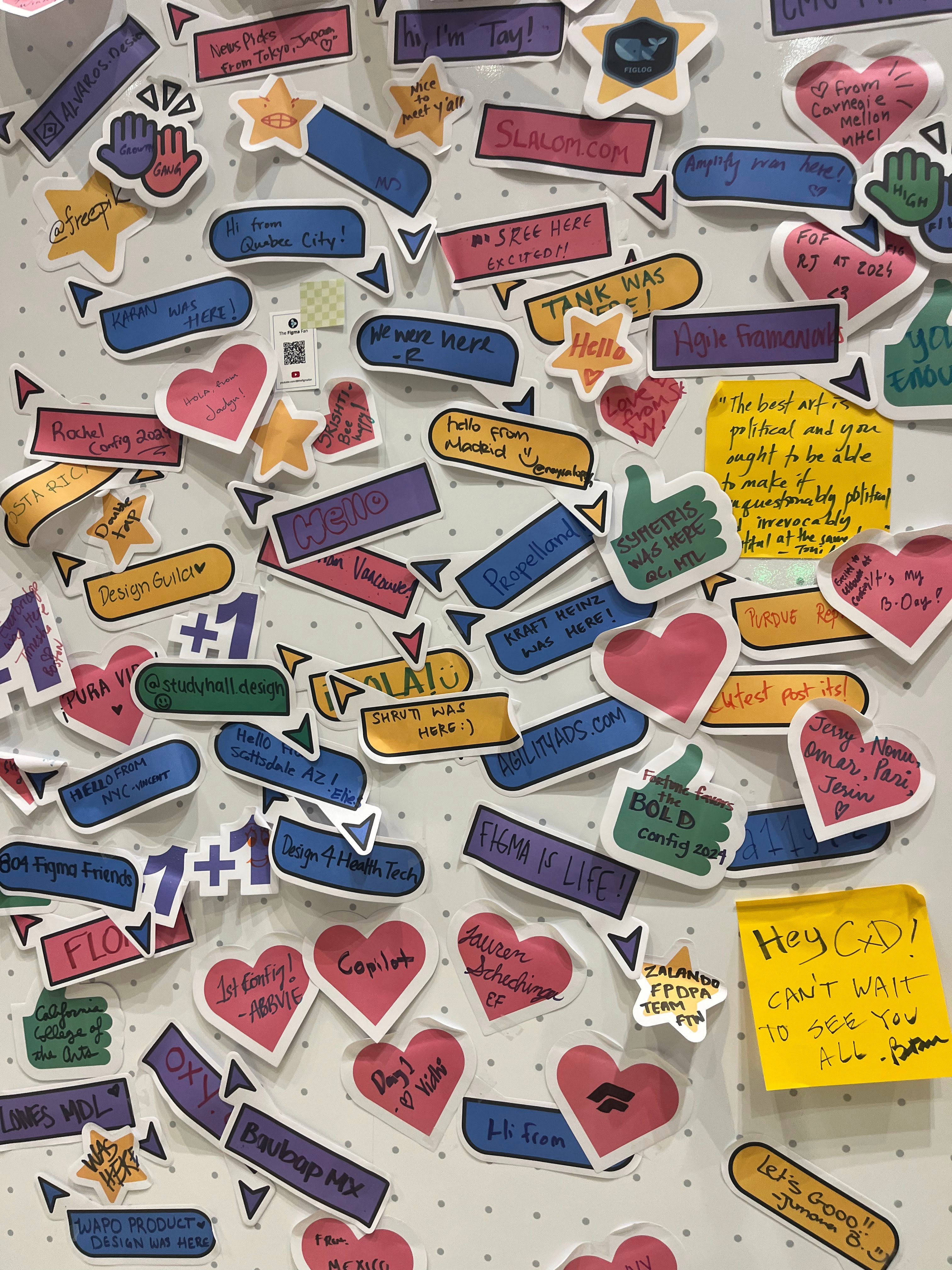 A wall covered in stickers and notes left by attendees at a design community conference
